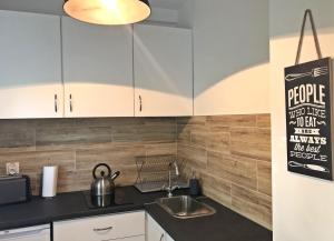 a kitchen with white cabinets and a sink at Apartament Swoboda in Poznań