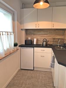 a kitchen with white cabinets and a sink at Apartament Swoboda in Poznań