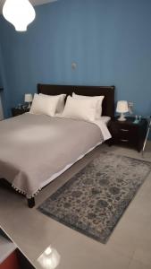 a bedroom with a large bed with two tables and a rug at Blue Studio in Nea Moudania