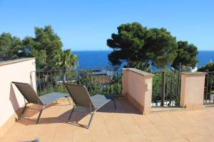 a patio with chairs and the ocean in the background at Aina in Cala Pi