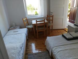 Cette chambre comprend deux lits, une table et des chaises. dans l'établissement Kwatery u Eve, à Dziwnów