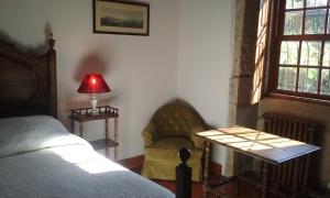 um quarto com uma cama, um candeeiro e uma cadeira em Quarto das Lamparinas em Ponte de Lima