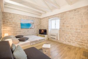 a bedroom with two beds and a tv and a brick wall at Olive Garden in Ston