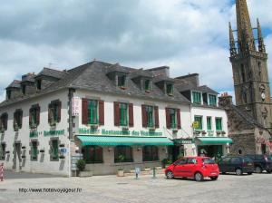 a red car parked in front of a building at Les Voyageurs in Sizun