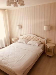 a bedroom with a large white bed with two tables at Classic Apartment in Boryspil