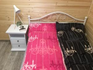 1 cama con ropa de cama rosa y negra y escritorio en Houseboat Ślesin, en Ślesin