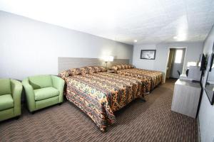 a hotel room with a bed and a green chair at Belcaro Motel in Denver
