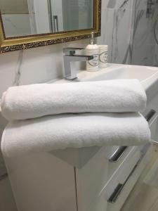 a white bathroom sink with two towels on it at Apartament Silence Baltic Royal Gold in Pobierowo