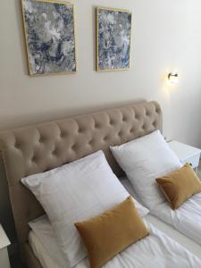 ein Bett mit zwei Kissen und zwei Bildern an der Wand in der Unterkunft Apartament Silence Baltic Royal Gold in Pobierowo