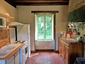 a kitchen with a white refrigerator and a window at moulin de Rimer in Auvers-le-Hamon