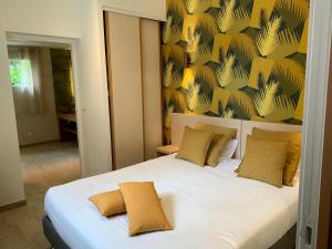 a bedroom with a white bed with a yellow wall at Hôtel Le Mistral in Porto-Vecchio