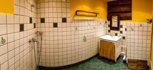 a bathroom with a sink and a white tiled wall at Dzikie Roztocze - Stara Chata in Krasnobród