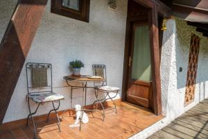 a porch with two chairs and a table and a dog at Agriturismo La Garzonera in Vergiate