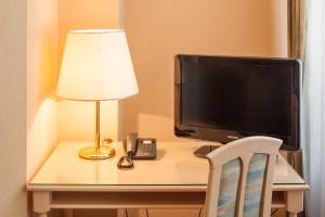 a desk with a television and a lamp and a lamp at Hotel Villa Auguste Viktoria in Ahlbeck