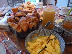 una mesa cubierta con platos de pan y un bol de fruta en Domaine de la Safranière - Chambre d'hote, en Saint-Léger