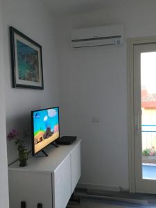 una televisione seduta su un mobile bianco in soggiorno di Maison Turquoise a Cala Gonone