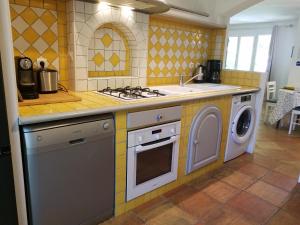 a kitchen with a stove and a washing machine at Entre Nîmes et Arles in Bellegarde