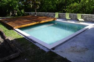 a swimming pool with a wooden deck and a retaining wall at Loustalneou in Saint-Pierre-de-Clairac