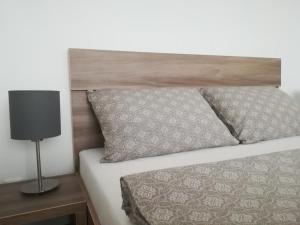 a bed with a wooden headboard and a lamp on a table at Apartment Amber Wind in Palanga