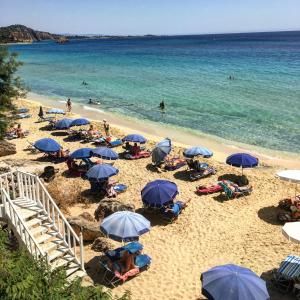 a beach with blue umbrellas and people in the water at Regina Apartments in Lassi