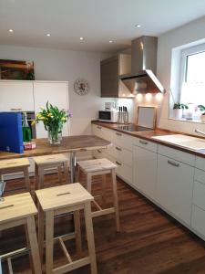 uma cozinha com armários brancos e mesas e cadeiras de madeira em Ulenspegel em Tating