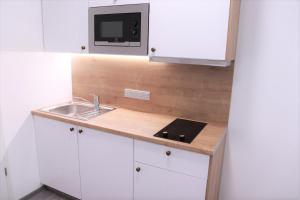 eine Küche mit weißen Schränken, einer Spüle und einer Mikrowelle in der Unterkunft JM Apartments in Hardegg