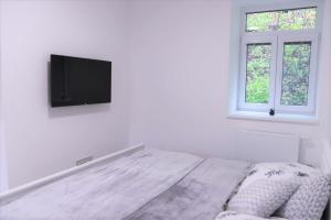 ein weißes Schlafzimmer mit einem Bett und einem Flachbild-TV in der Unterkunft JM Apartments in Hardegg