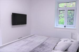 a white bedroom with a bed and a flat screen tv at JM Apartments in Hardegg