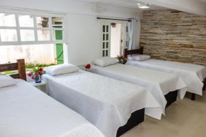 a group of three beds in a room at Pousada Paraiso do Alto in Paraisópolis