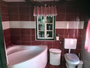 a bathroom with a tub and a toilet and a window at Holiday home Hižica v plavem trnacu in Gornja Stubica