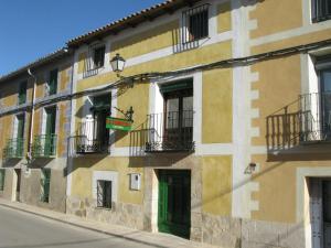 ein Gebäude mit grüner Tür und Balkonen auf einer Straße in der Unterkunft La Carpintería Casa Rural in Romanones
