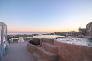 a hot tub on the side of a building with the sunset at Sea & Stone Residence Mykonos in Platis Yialos Mykonos