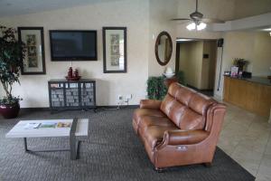 ein Wohnzimmer mit einem Ledersofa und einem TV in der Unterkunft Sunrise Inn in Las Vegas