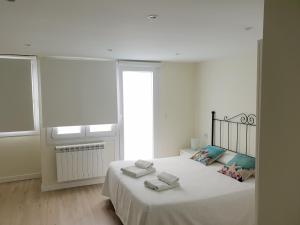 biała sypialnia z łóżkiem i ręcznikami w obiekcie Apartamentos-Bermeo w mieście Bermeo