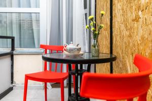 a table with two red chairs and a vase with flowers at Boutique Hotel MOJO in Tbilisi City