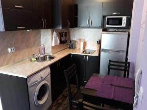 a kitchen with a sink and a table with a washing machine at Studio-Pomorie in Pomorie