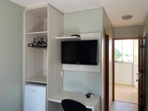 a room with a wall with a tv and a desk at Hotel Central de Anápolis in Anápolis