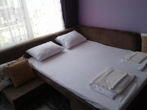 a bed with white sheets and pillows and a window at Studio-Pomorie in Pomorie