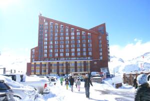 um grupo de pessoas andando na neve em frente a um edifício em Departamento Valle Nevado Ski Resort Chile Ski in - Ski out em Valle Nevado