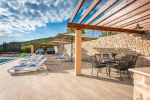 un patio con mesa, sillas y pared de piedra. en Villa Danica, en Vid