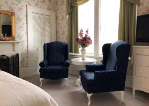 sypialnia z 2 niebieskimi krzesłami i łóżkiem w obiekcie Balmoral House Bed & Breakfast w mieście St. John's
