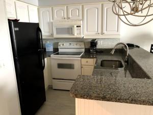 a kitchen with white cabinets and a black refrigerator at Ocean Walk Resort 508 in Daytona Beach