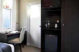 a room with a desk and a refrigerator at Vulcan Hotel Sydney in Sydney