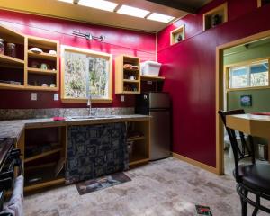 uma cozinha com paredes vermelhas e um lavatório em Honu Hale em Volcano