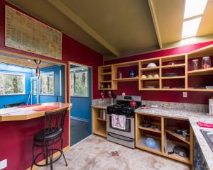 uma cozinha com paredes vermelhas, um balcão e um fogão em Honu Hale em Volcano