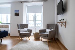 a living room with two chairs and a tv at Belém - Fully equiped Studio in Lisbon