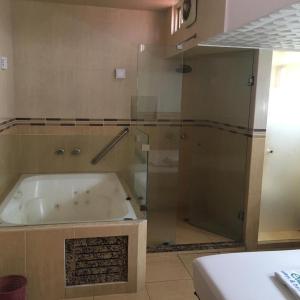 La salle de bains est pourvue d'une baignoire et d'une porte de douche en verre. dans l'établissement Hotel & suites elba, à Toluca