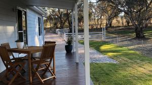 a patio with a table and chairs on a porch at Rosewood Cottage in Grattai +15 photos