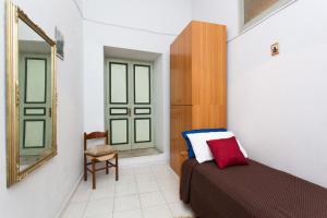 1 dormitorio con cama, espejo y silla en House Ròdue The Historic Center Palermo, en Palermo