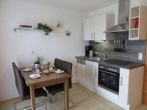 a kitchen with a wooden table with chairs and a stove at Ferienwohnung Brigitte Perner in Nussdorf am Attersee